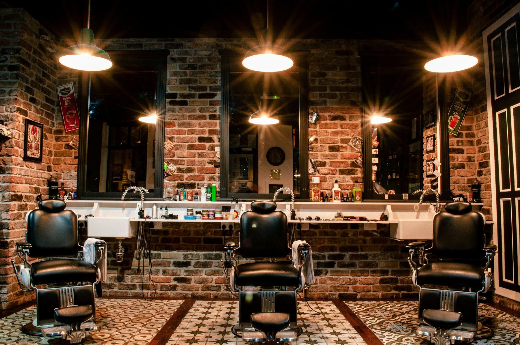Three leather barber chairs under warm lights