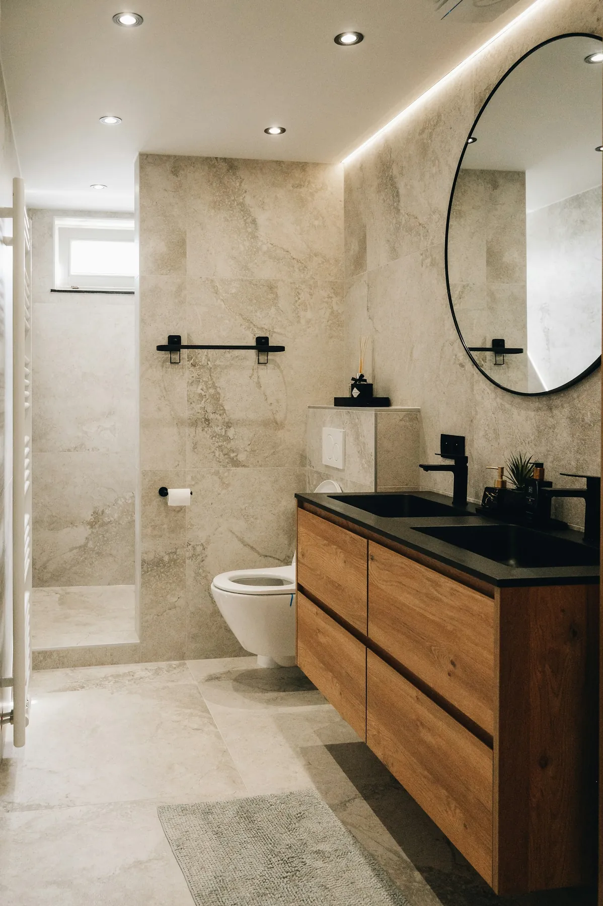 Bathroom with stone-effect tiles, wooden vanity and round mirror