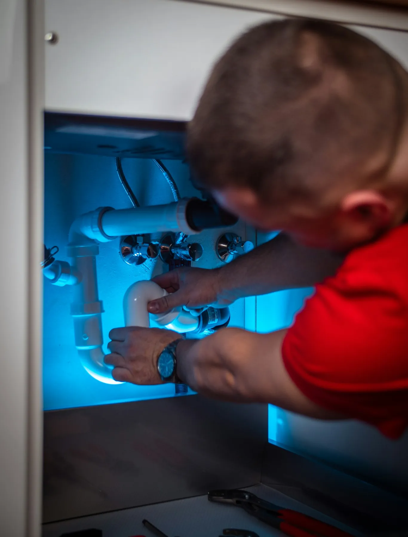 Plumber fitting new pipework under a kitchen sink