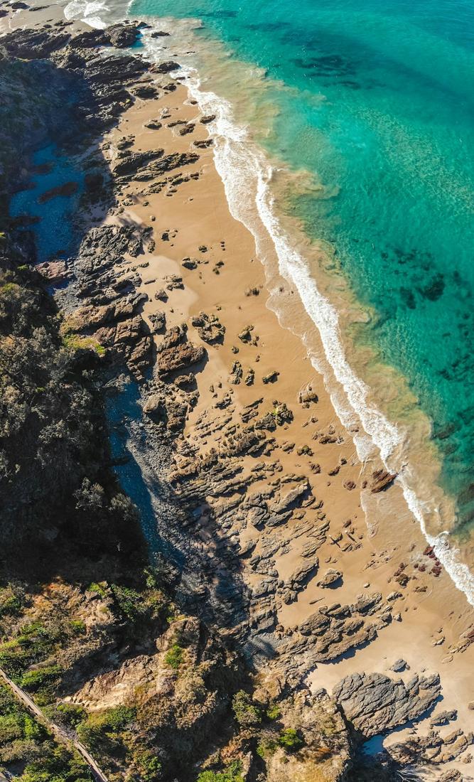 Aerial view of a turquoise coastline and sandy track