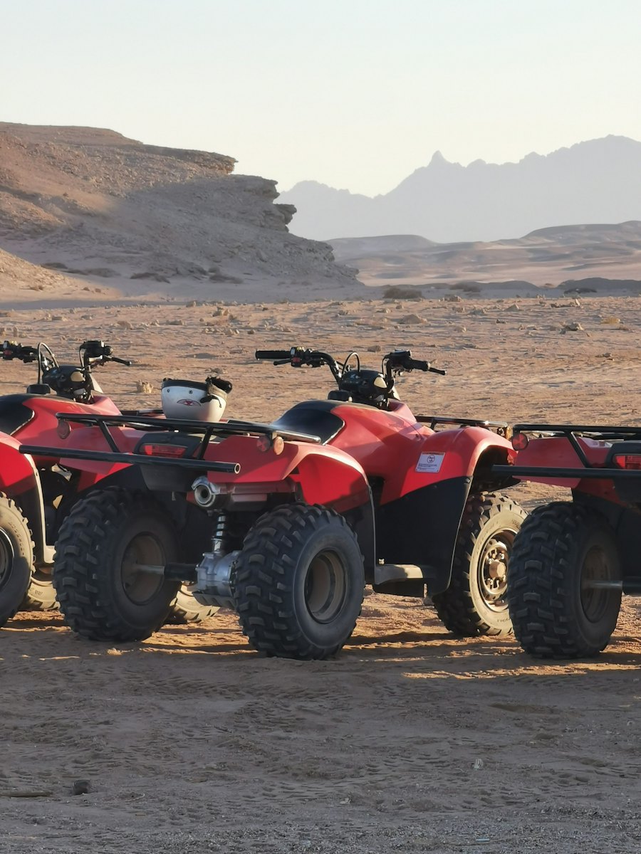Red quad bikes lined up on a dirt track