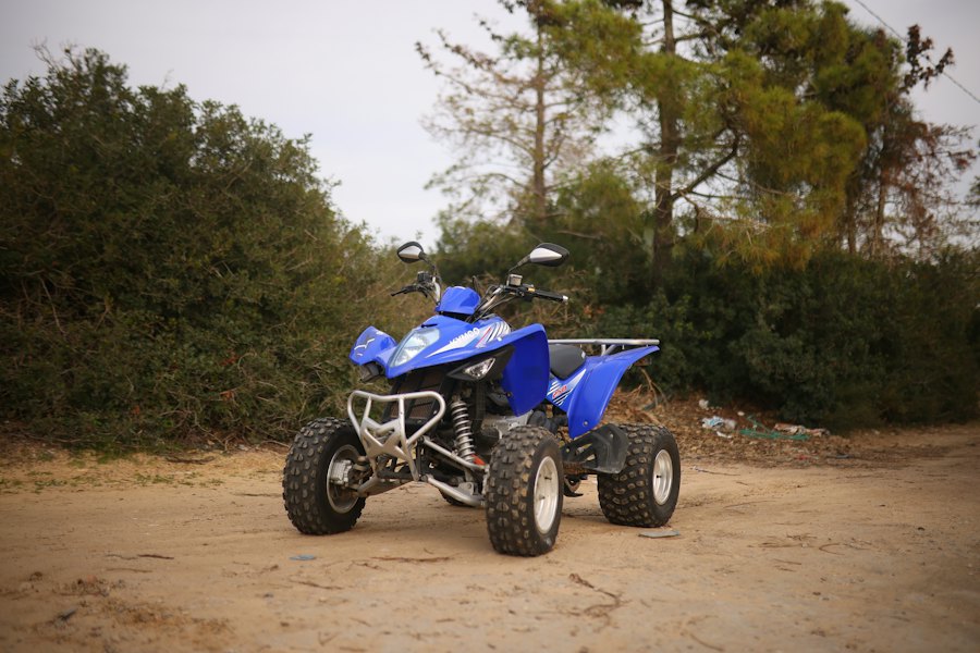 Small blue sport quad parked on a dirt track