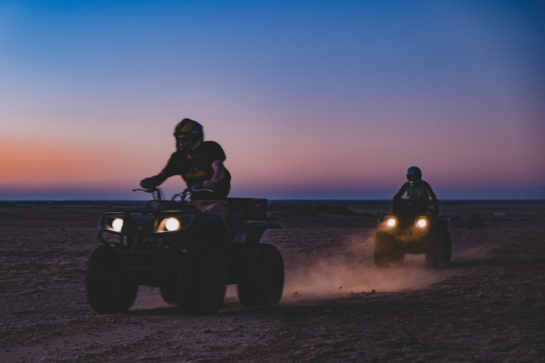 Two quads with headlights on at dusk
